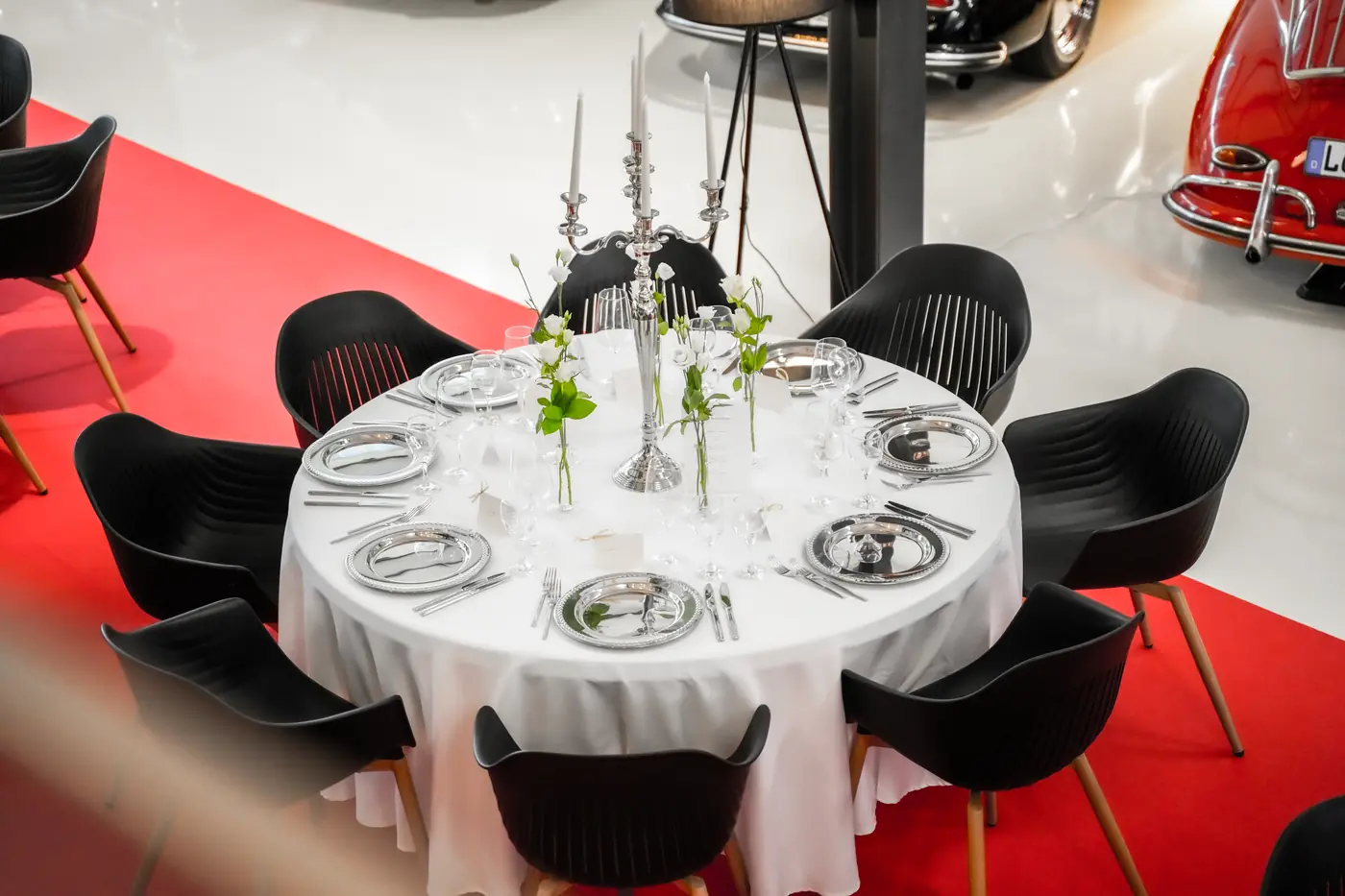 Runder Tisch mit weißer Tischdecke auf rotem Teppich