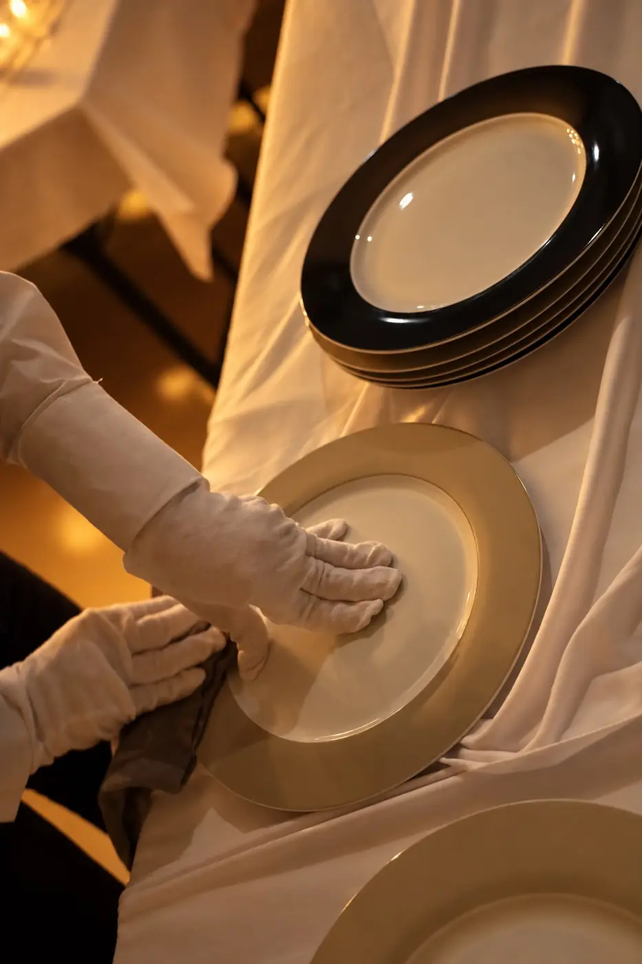 Servicekraft mit weißen Handschuhen am Teller