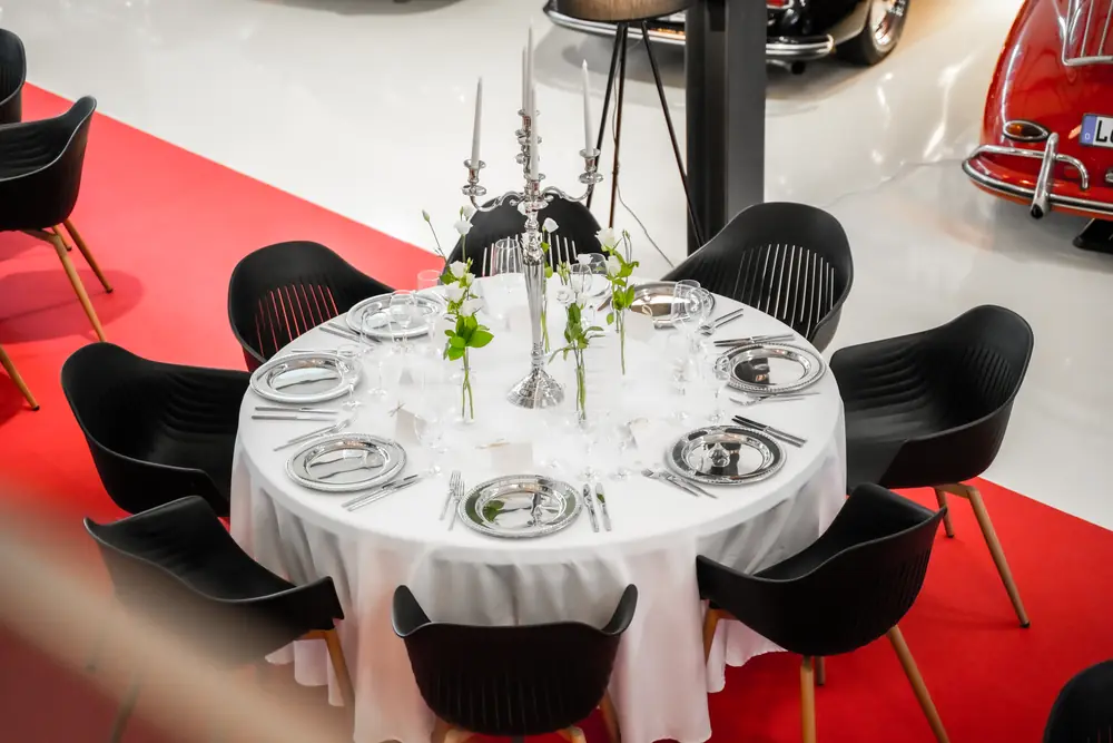 Festlich gedeckter runder Tisch vor Oldtimern